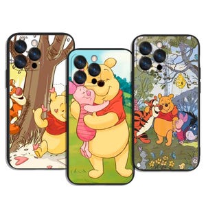 Könnte beinhalten: Drei Handyhüllen mit Illustrationen von Winnie Puuh und seinen Freunden. Die Hüllen zeigen farbenfrohe Szenen von Puuh, Ferkel, Tiger und I-Aah. Die Hüllen haben schwarze Ränder und sind für ein Smartphone konzipiert.