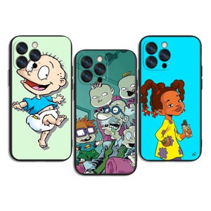 Puede incluir: Tres fundas de teléfono con diseños de personajes de dibujos animados. Una funda presenta a un bebé con una camisa azul y un pañal sobre un fondo verde claro. Otra funda tiene un grupo de personajes sobre un fondo turquesa. La tercera funda muestra a una niña con un vestido amarillo sobre un fondo azul.