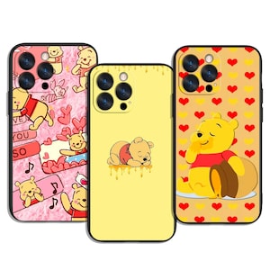May include: Three phone cases featuring Winnie the Pooh designs. One case is pink with Pooh and hearts, another is yellow with a sleeping Pooh, and the third is yellow with Pooh and honey. The cases have black borders.