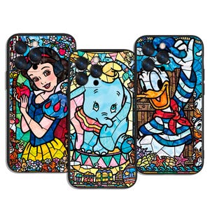 Op de afbeelding: Set van drie telefoonhoesjes met glas-in-loodontwerpen. Eén hoesje toont Sneeuwwitje met een appel, een ander Dumbo de olifant en de derde Donald Duck. Elk hoesje heeft een zwarte rand.