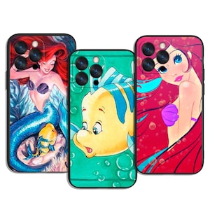 May include: Three phone cases featuring cartoon mermaid characters. The cases have black borders and colorful illustrations. One case has a mermaid with red hair and a blue tail. Another case has a yellow fish. The third case has a mermaid with red hair.