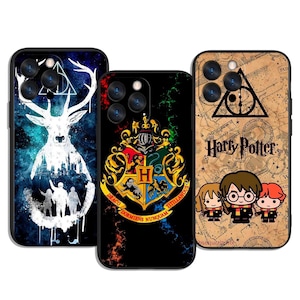 May include: Three phone cases with Harry Potter-themed designs. One case features a white stag silhouette with a cityscape and figures against a blue and black background. Another displays the Hogwarts crest. The third case has a map design with the words "Harry Potter" and cartoon characters.