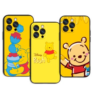 Puede incluir: Tres fundas amarillas para teléfono con diseños de Winnie the Pooh. Una funda muestra a Pooh con botes de miel, otra tiene a Pooh con el logo de Disney Pooh, y la tercera representa a Pooh con un bote de miel. Cada funda tiene un borde negro.