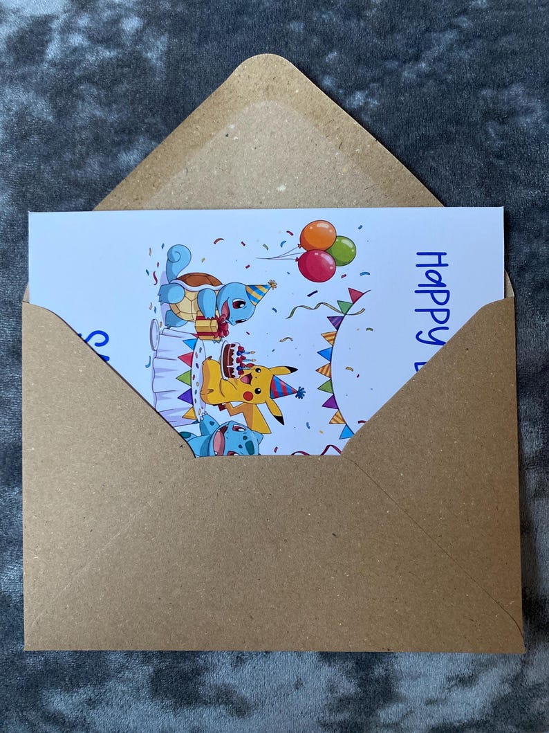 K&ouml;nnte beinhalten: Eine Geburtstagskarte mit Zeichentrickfiguren, darunter ein gelbes Pikachu, ein blaues Schiggy und eine blau-wei&szlig;e Kreatur, die mit Kuchen und Luftballons feiern. Die Karte befindet sich in einem braunen Umschlag, mit dem Wort "Happy" sichtbar.