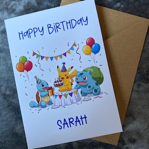K&ouml;nnte beinhalten: Eine wei&szlig;e Geburtstagskarte mit dem Text "HAPPY BIRTHAY SARAH" in Blau. Die Karte zeigt Cartoonfiguren, Luftballons, Konfetti und einen Kuchen. Ein brauner Umschlag befindet sich hinter der Karte.