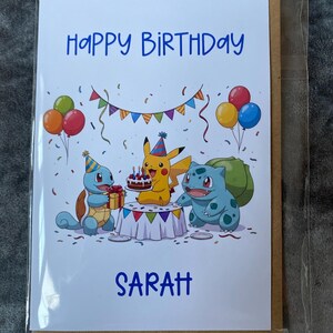 K&ouml;nnte beinhalten: Geburtstagskarte mit dem blauen Schriftzug "Happy Birthday Sarah". Die Karte zeigt eine farbenfrohe Illustration von Pikachu, Schiggy und Bisasam an einem Tisch mit Kuchen und Luftballons.