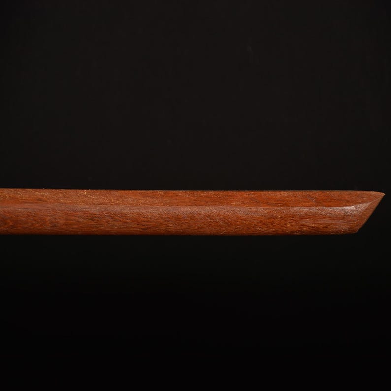 Pu&ograve; includere: Primo piano di un vassoio di legno con finitura marrone rossiccio scuro. Il vassoio ha una forma rettangolare con un bordo smussato su un'estremit&agrave;. La venatura del legno &egrave; visibile e il vassoio sembra fatto a mano.