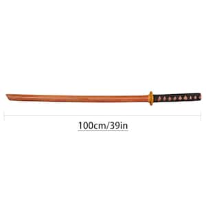 Pu&ograve; includere: Una katana di legno, lunga 100 cm, con una lama marrone e un'impugnatura nera e marrone. La katana presenta una guardia dorata.
