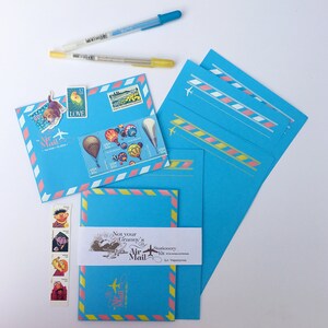May include: A set of blue stationery with pink and yellow accents. The stationery features a whimsical design with hot air balloons, a plane, and the text "Not your Granny's Air Mail Stationery Kit".