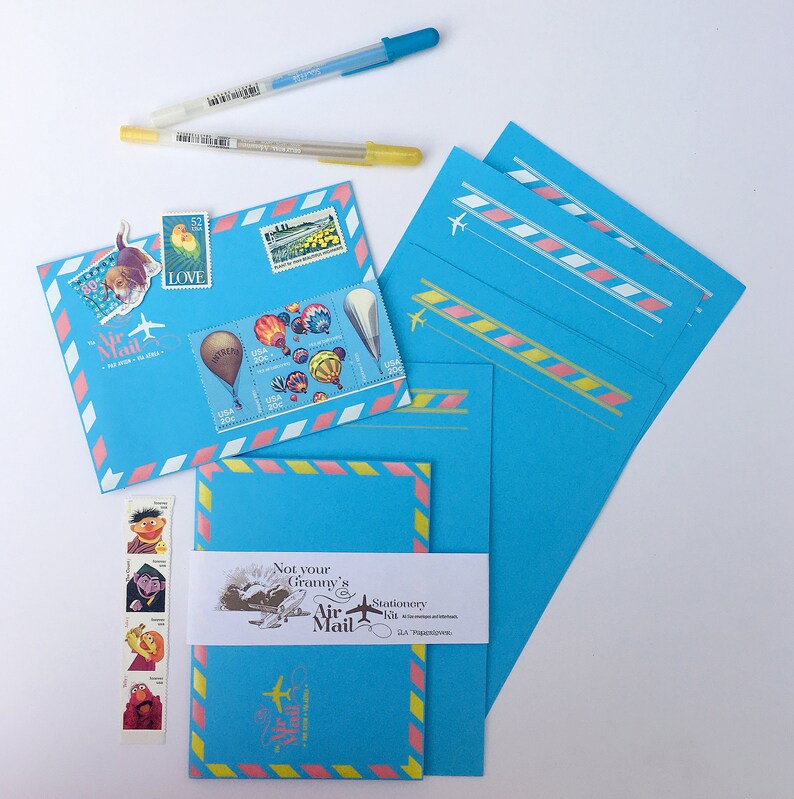 May include: A set of blue stationery with pink and yellow accents. The stationery features a whimsical design with hot air balloons, a plane, and the text "Not your Granny's Air Mail Stationery Kit".