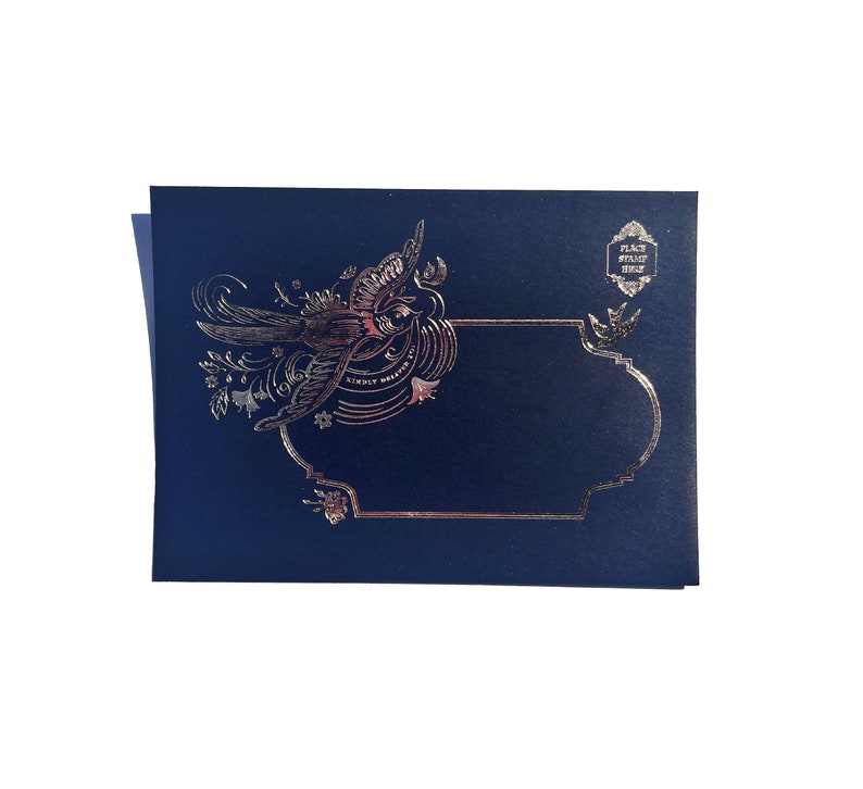May include: A navy blue invitation card with gold foil accents. The card features an ornate bird design and a decorative frame for text. The words "KINDLY REQUESTED" are printed on the card. The upper right corner has the text "PLACE STAMP HERE".