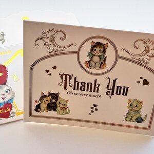 Puede incluir: Un juego de tarjetas de felicitaci&oacute;n de estilo vintage con tem&aacute;tica de gatos. La tarjeta principal dice "Thank You" con ilustraciones de gatitos. El sobre presenta un gato y las palabras "Via Air Mail". La paleta de colores incluye crema, marr&oacute;n, rojo y azul.