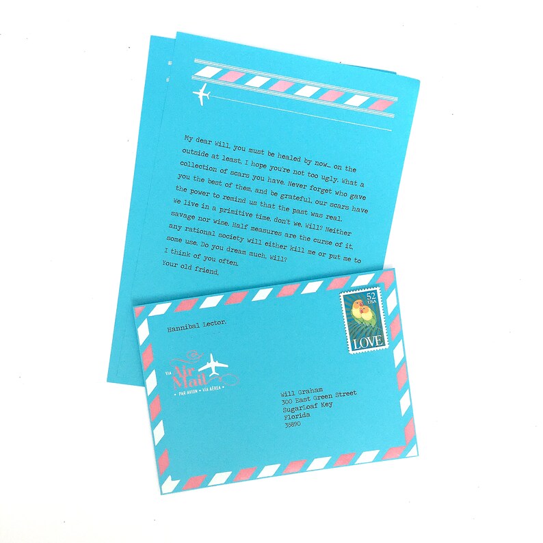 May include: A blue and pink paper airplane envelope with a handwritten letter inside. The letter is addressed to Vill Grahan, 300 East Green Street, Sugarloaf Key, Florida 33080. The envelope has a stamp with two lovebirds and the word "LOVE" printed on it.