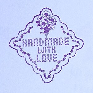 Puede incluir: Un dise&ntilde;o floral morado y blanco con las palabras "HANDMADE WITH LOVE" en un marco en forma de diamante. El texto est&aacute; en estilo de punto de cruz, con un ramo de flores en la parte superior.