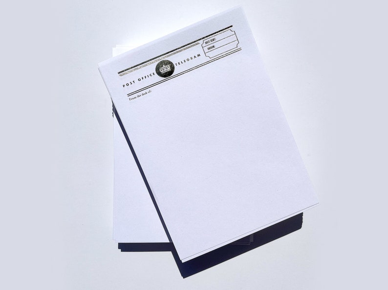 May include: A stack of blank white paper telegram forms with a black and silver printed header that reads "Post Office Telegram". The header also includes a crown graphic.
