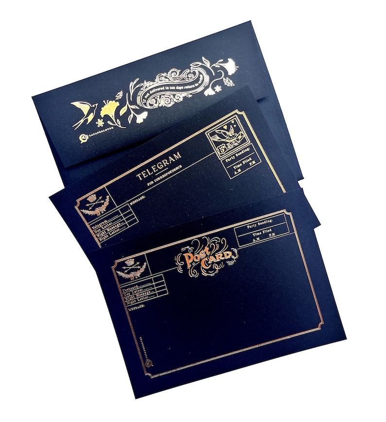 May include: A stack of navy blue stationery with gold foil accents. The set includes a postcard and telegram design. The postcard reads "Post Card" in an ornate font. The telegram reads "Telegram for Correspondents".