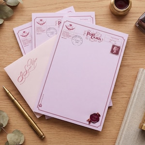 Peut inclure: Un ensemble de papeterie avec des cartes postales roses, une enveloppe avec l'inscription "I Love You" et un stylo doré sur une surface en bois. Les cartes postales ont un design vintage avec des timbres et un sceau de cire.