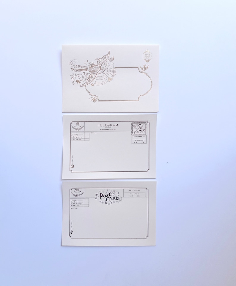 Puede incluir: Tres postales en blanco de estilo vintage con detalles dorados. La tarjeta superior presenta un dise&ntilde;o de p&aacute;jaro. La tarjeta del medio dice "TELEGRAMA" y la tarjeta inferior dice "TARJETA POSTAL".