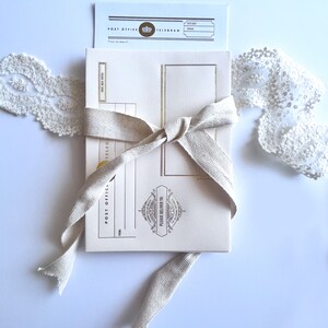 May include: A cream-colored postcard with gold accents and a brown ribbon tied around it. The postcard has the words "Post Office Telegram" printed on it. The postcard is on a white background.