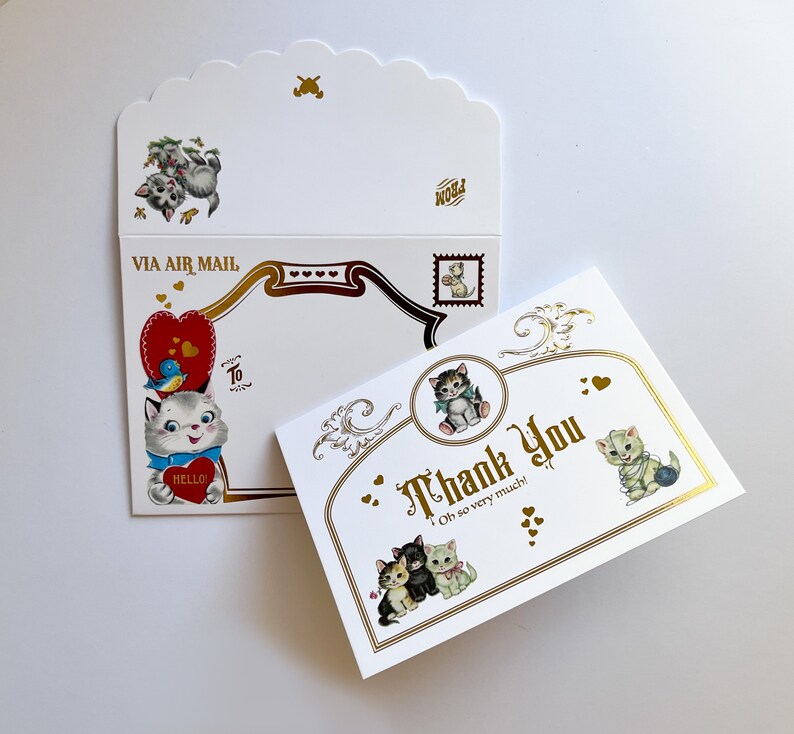 Puede incluir: Un juego de papeler&iacute;a de estilo vintage con ilustraciones de gatitos. El juego incluye un sobre con borde festoneado con el texto "Via Air Mail" y una tarjeta de "Thank You" con detalles dorados y la frase "Oh so very much!"