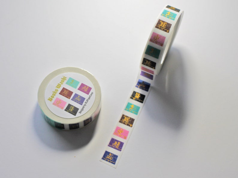 K&ouml;nnte beinhalten: Eine Rolle wei&szlig;es Washi-Klebeband mit einem bunten Design aus geschlossenen B&uuml;chern mit goldenen Schriftz&uuml;gen. Das Band ist mit "Booko Washi" und "Designed by LL Magazine" beschriftet.