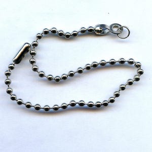 May include: A silver ball chain with a silver clasp. The chain is about 18 inches long.