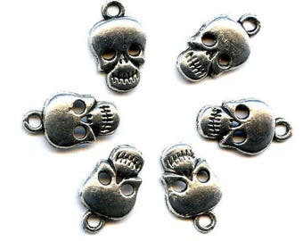 Könnte beinhalten: Sechs silberne Totenkopf-Anhänger mit einer Schlaufe zum Aufhängen. Die Totenköpfe haben ein detailliertes Design mit Augenhöhlen, einer Nase und einem Mund.