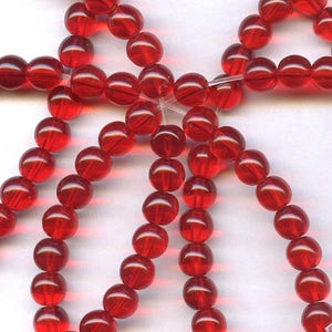 May include: A strand of red glass beads. The beads are round and have a smooth, shiny finish.