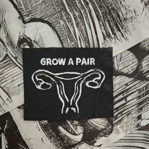 May include: A black square with the words "GROW A PAIR" in white, above a white illustration of a uterus and fallopian tubes. The background has a textured, black and white design.