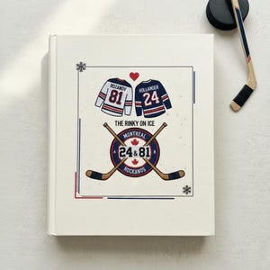 Può includere: Un taccuino color crema con un design a tema hockey. La copertina presenta due maglie da hockey, un cuore e il testo "THE RINKY ON ICE MONTREAL 24 & 81 HOCKANOS". Sono visibili un disco e una stecca da hockey.