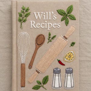 May include: Embroidered cookbook titled "Will's Recipes" with kitchen-themed illustrations. Features a whisk, wooden spoon, rolling pin, lemon slice, chilli pepper, salt and pepper shakers, and herbs. Beige cover with white embroidered text and details.