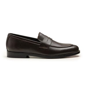 May include: A single brown leather loafer shoe with a textured surface. The shoe has a rounded toe, a penny strap, and a black sole with white stitching. The shoe is designed for casual or formal wear.