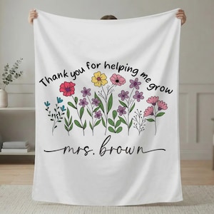 Puede incluir: Manta blanca con un diseño floral y el texto "Thank you for helping me grow mrs. brown" en escritura negra. Las flores son en tonos rojos, amarillos, rosas, morados y azules, con tallos y hojas verdes. Un regalo considerado.