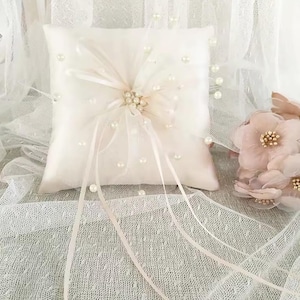 Cuscino porta fedi in raso beige con decorazioni di perline.