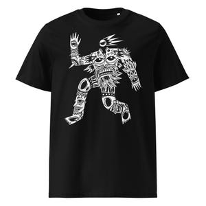 Puede incluir: Camiseta negra con un gráfico blanco de una figura estilizada con múltiples ojos y patrones intrincados. El diseño tiene una estética tribal o de arte popular, en una pose dinámica. La camiseta está hecha de un material suave.