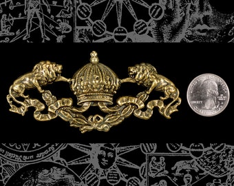 Puede incluir: Un emblema metálico dorado con una corona flanqueada por dos leones. El emblema mide aproximadamente 7,6 cm de largo e incluye adornos decorativos. Se incluye una moneda de 25 centavos estadounidense para comparar el tamaño. El fondo es negro con ilustraciones grises.