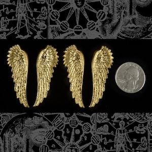 May include: Four gold-colored metal angel wings with a feathery design. The wings are arranged in two pairs, with the wings in each pair facing each other.