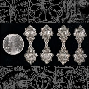 May include: Four silver spoon-shaped charms with a decorative scallop design. The charms are arranged in a row against a black background.