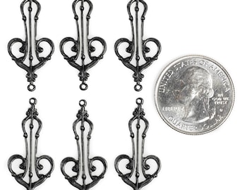 May include: Six black metal decorative embellishments with a filigree design. The embellishments are about the size of a US quarter.