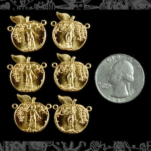 Op de afbeelding: Zes goudkleurige metalen bedels in de vorm van appels met een gestileerd beeld van een persoon die in de appel staat. De bedels hebben twee gaten om aan een ketting of armband te bevestigen. Een Amerikaanse kwartje is getoond ter groottevergelijking.