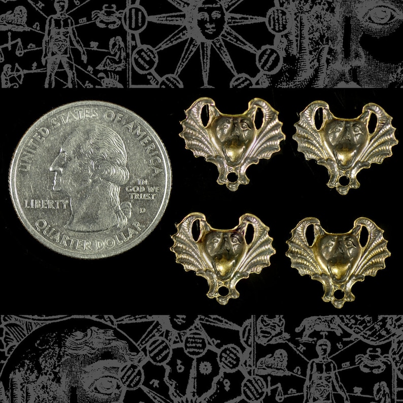 May include: Four gold-colored metal pendants with a bat-like face design, next to a U.S. quarter. The pendants have a detailed, textured appearance. The background is black with faint, stylized illustrations.