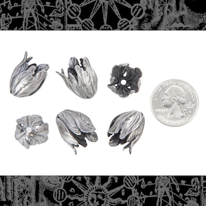 May include: Silver-coloured metal tulip-shaped bead caps. The caps have detailed, textured surfaces, resembling tulip flower petals. A US quarter is included for size comparison. The caps are likely for jewellery making or crafting.