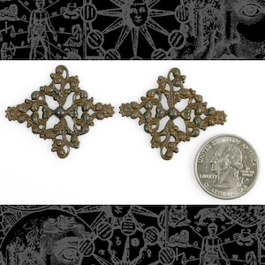 May include: Two antique-looking metal decorative pieces in the shape of a diamond with intricate floral designs. The pieces are about the size of a UK 20 pence coin.