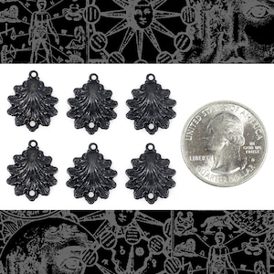 Puede incluir: Seis abalorios decorativos de metal negro con forma de concha estilizada y superficie texturizada. Los abalorios son aproximadamente del tamaño de una moneda de 25 centavos de dólar estadounidense.