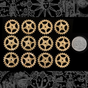 Könnte beinhalten: Zwölf goldfarbene Metallräder mit filigranen Designs, angeordnet in drei Reihen zu vieren auf schwarzem Hintergrund. Eine silberne US-Viertel-Dollar-Münze ist zur Größenbestimmung enthalten.