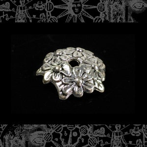 Puede incluir: Cuentas de metal plateadas con diseño de flores. La cuenta tiene un agujero en el centro para enhebrar.