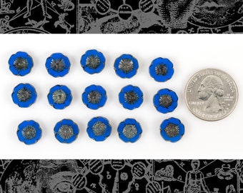 Könnte beinhalten: Eine Sammlung von 15 blauen und silbernen Knöpfen in Blumenform. Die Knöpfe sind in drei Reihen zu fünf angeordnet. Eine US-amerikanische 25-Cent-Münze dient als Größenvergleich.
