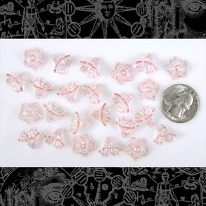 Può includere: Una collezione di perline di vetro rosa iridescente a forma di fiore. Le perline sono circa delle dimensioni di una moneta da 25 centesimi di euro.