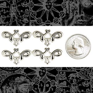 May include: Four silver-toned metal decorative embellishments with a scroll design. The embellishments are about the size of a US quarter.