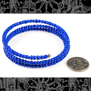 May include: A blue beaded bracelet with a silver clasp. The bracelet is coiled and measures approximately 5 cm in diameter. A US quarter is shown for scale.